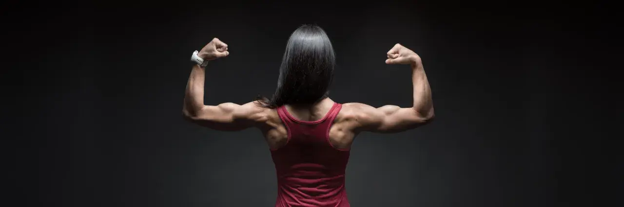 Mujer con espalda musculosa y brazos flexionados, mostrando su fuerza. El óxido nítrico para qué sirve: potencia el rendimiento deportivo.