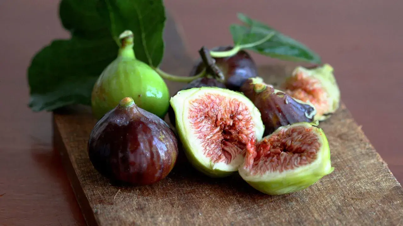 Frescos higos verdes y morados, algunos cortados, listos para comer.