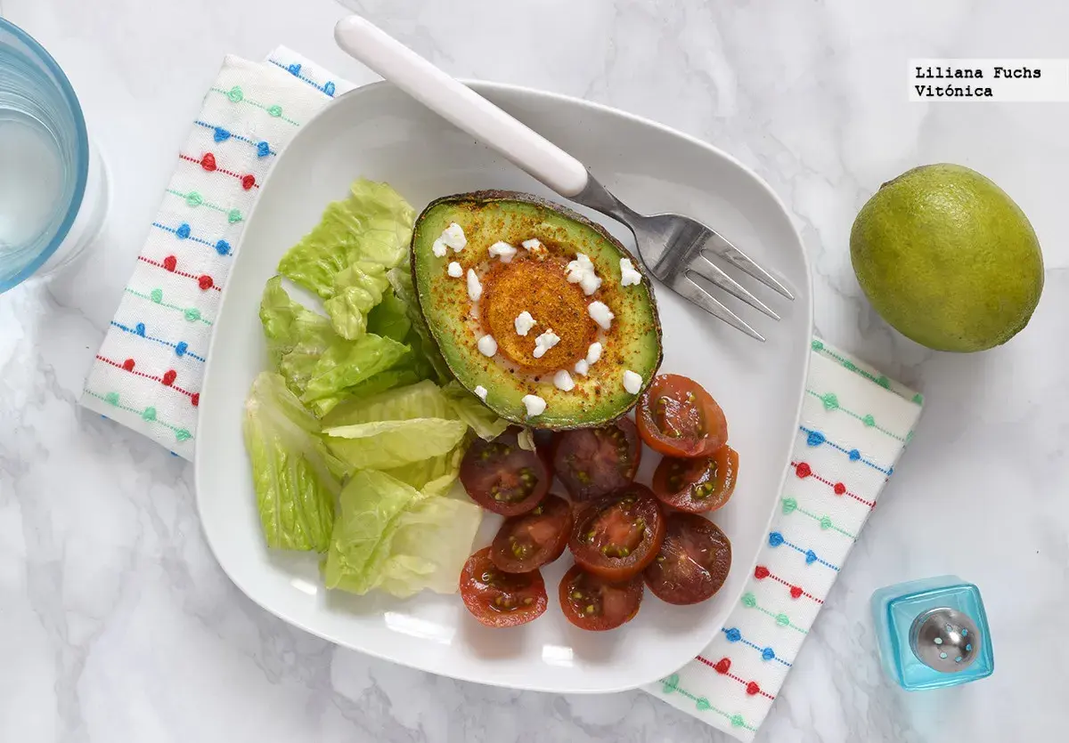 Aguacate horneado con queso y especias, acompañado de lechuga y tomates cherry. Un ejemplo de deliciosos alimentos cetogenicos.