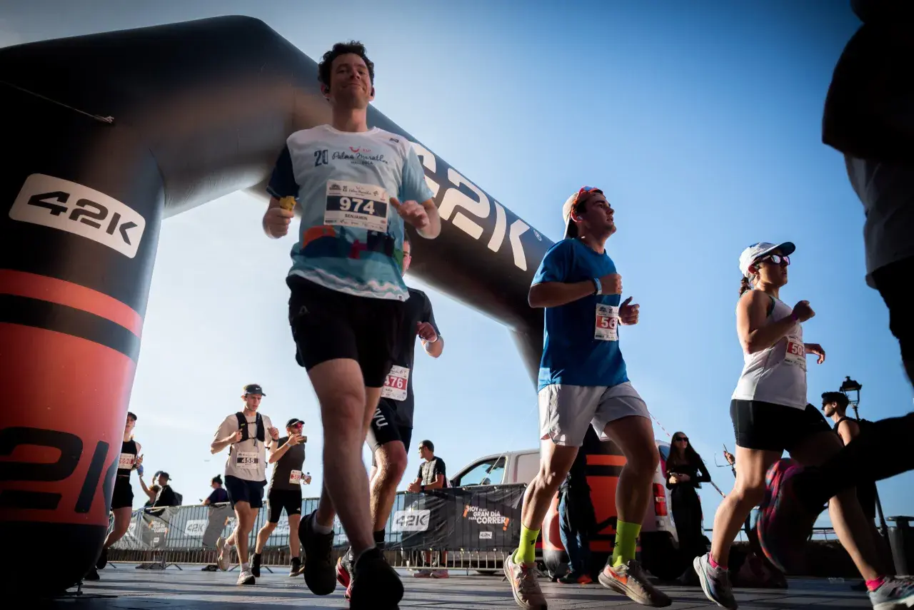 Corredores cruzan la meta de la media maratón bajo un arco inflable. El dorsal 974 destaca en un participante.