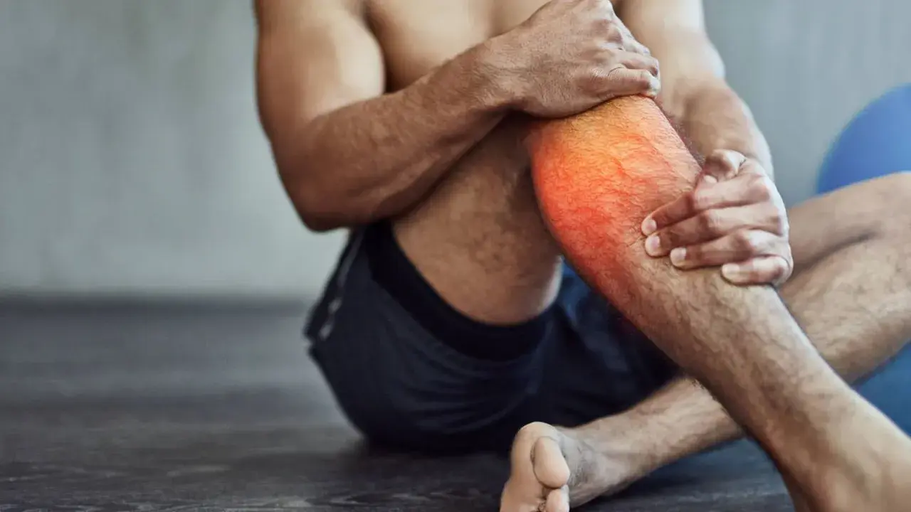 Hombre con dolor en la pantorrilla, con zona roja resaltada. A veces, es bueno hacer ejercicio con agujetas para fortalecer.