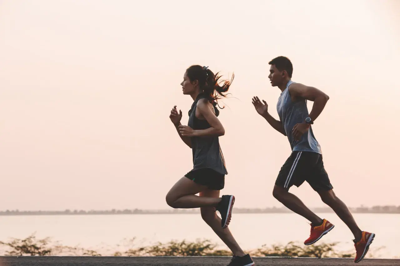 Pareja corriendo al amanecer. Para mantener la energía, es importante saber como tomar electrolitos.