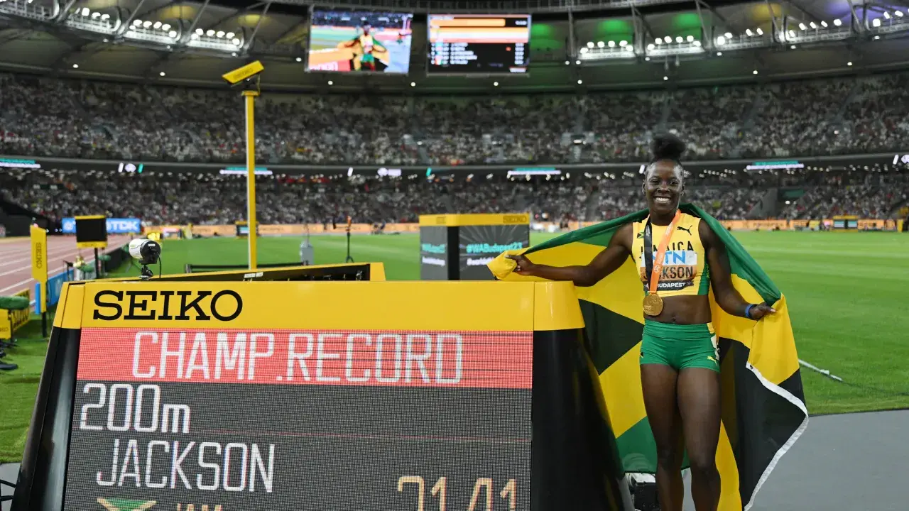Shericka Jackson, campeona y récord en 200m, celebra con la bandera de Jamaica y su medalla de oro.
