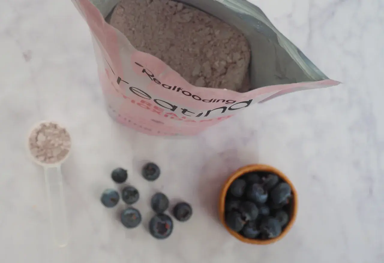 Bolsa de creatina, cucharada de polvo y arándanos. Consulta sobre creatina y embarazo.