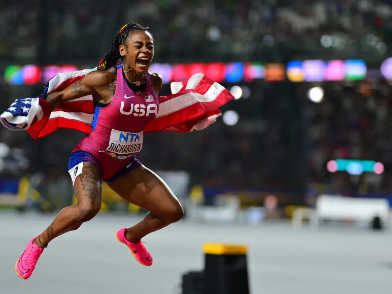 Sha'Carri Richardson, campeona 100 metros femeninos atletismo, celebra con la bandera de EE. UU. tras ganar.