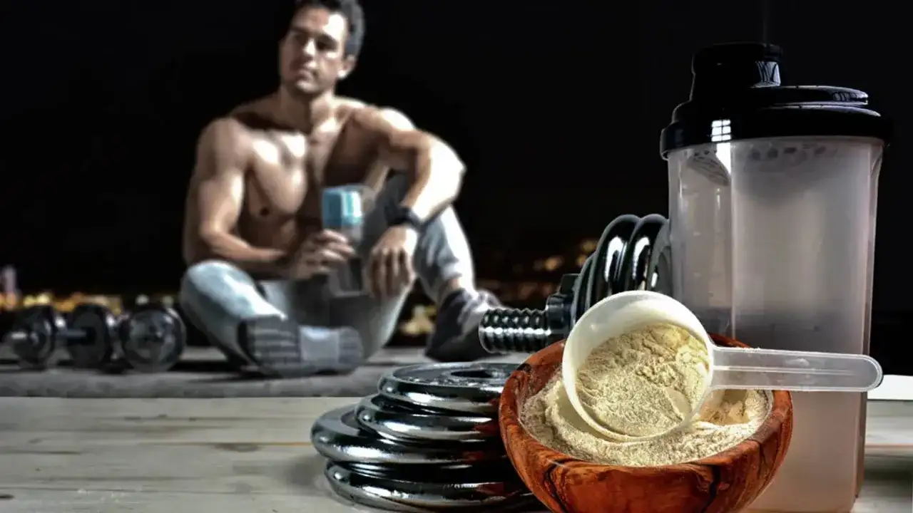 Un hombre musculoso descansa con pesas y un batido. El ácido aspártico para qué sirve: ayuda en la recuperación muscular y la energía.