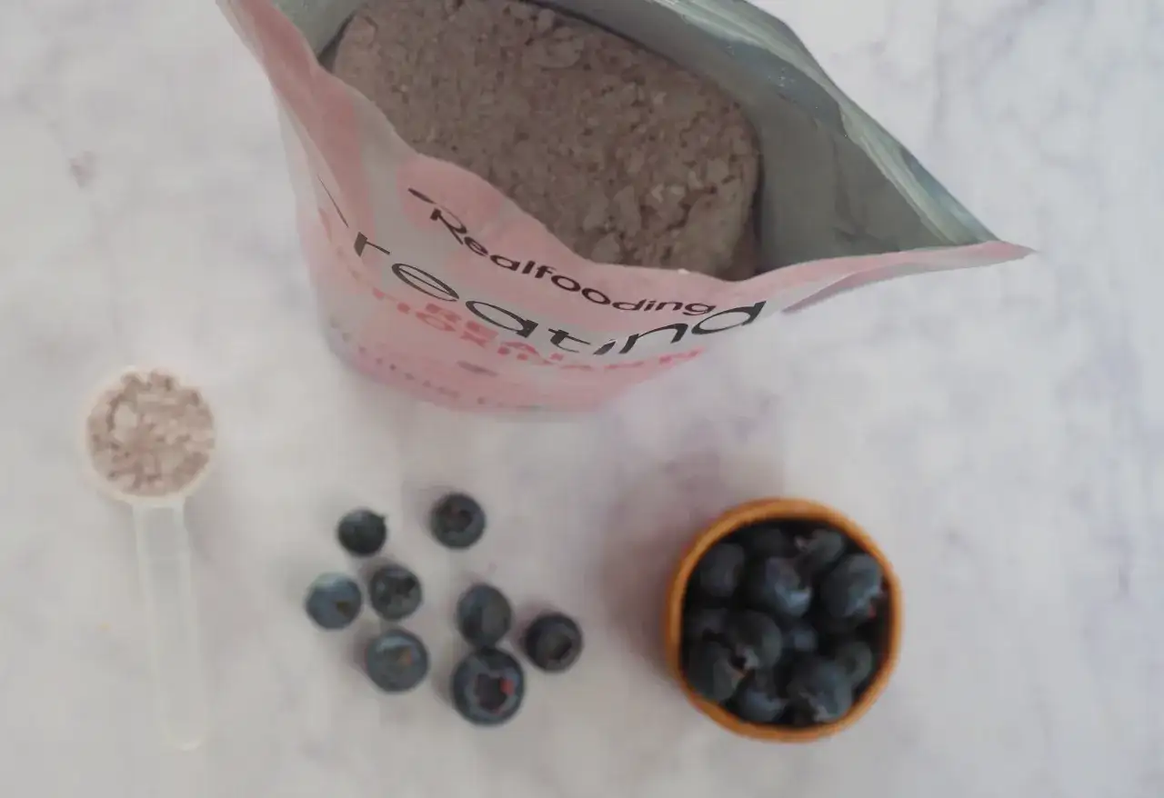 Bolsa de creatina, cucharada de polvo y arándanos. Consulta sobre creatina y embarazo.