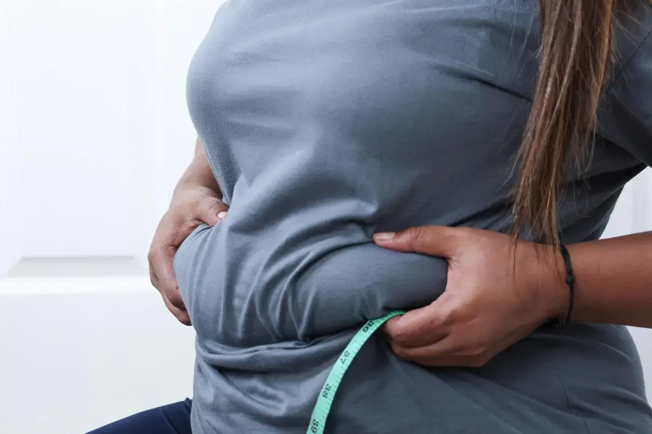 Persona se mide la cintura, preocupada porque el pan engorda el abdomen.