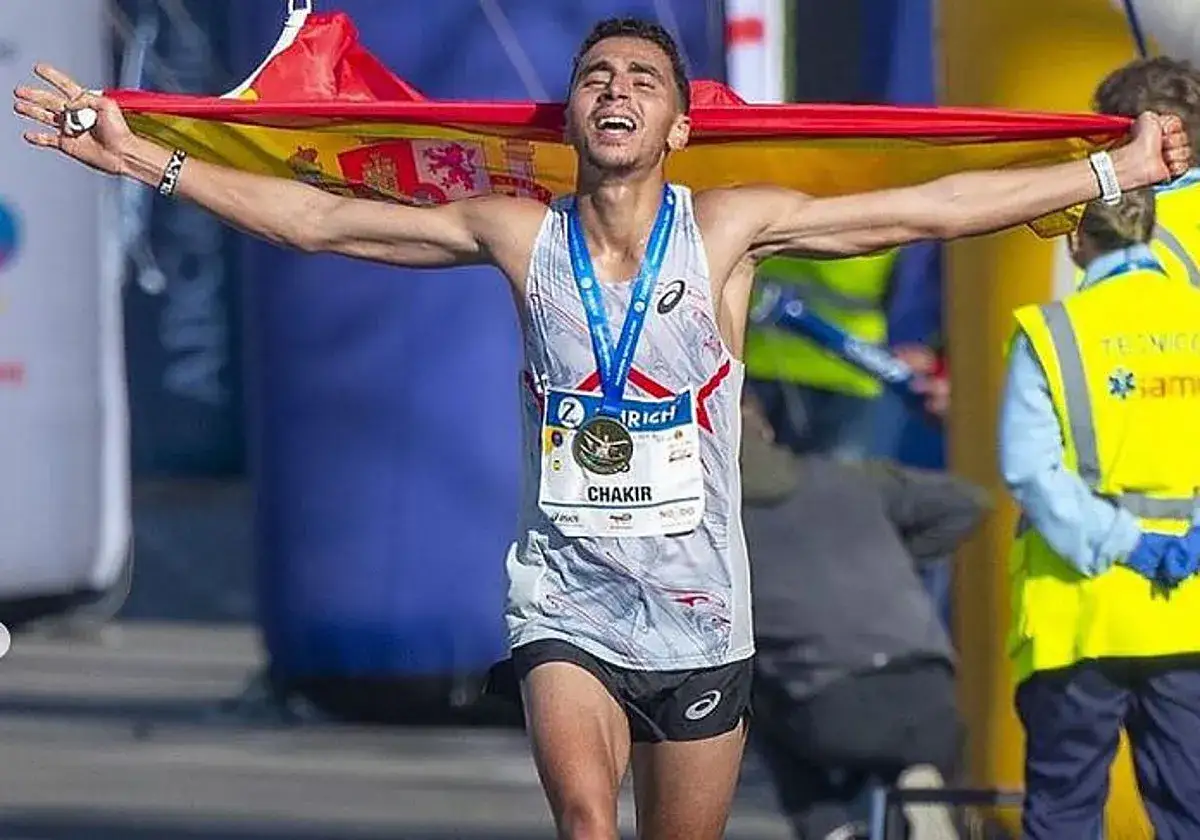 Ibrahim Chakir celebra su victoria en la maratón, ondeando la bandera española con orgullo y luciendo su medalla.