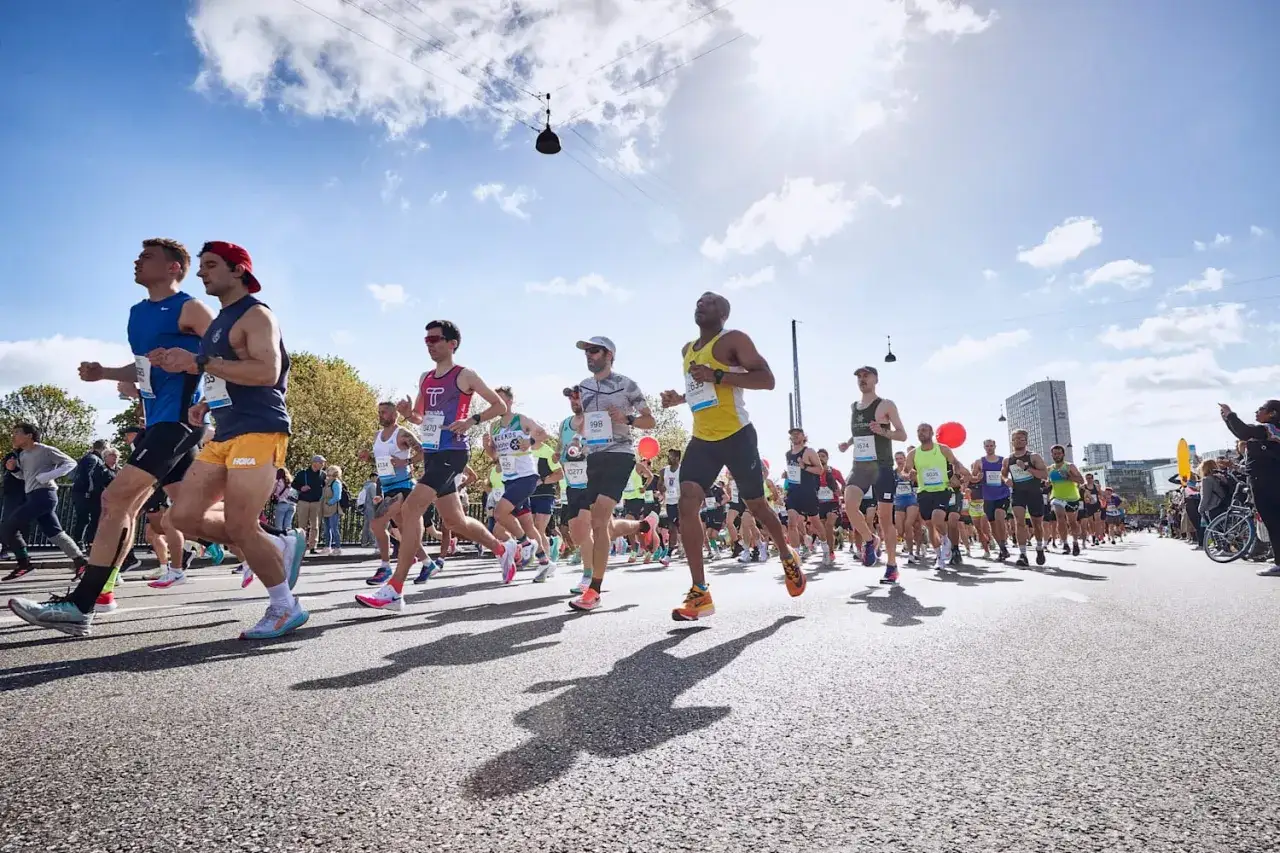 Corredores en una marat&oacute;n, con el sol brillando. Consejos para saber como evitar el flato al correr y disfrutar de la carrera.