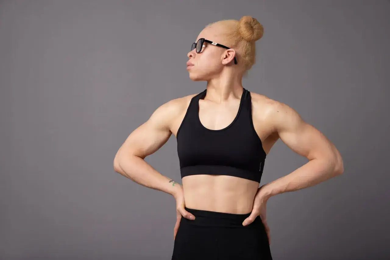 Adiaratou Iglesias, con su cabello rubio recogido y gafas, luce un top deportivo negro y muestra sus fuertes brazos.