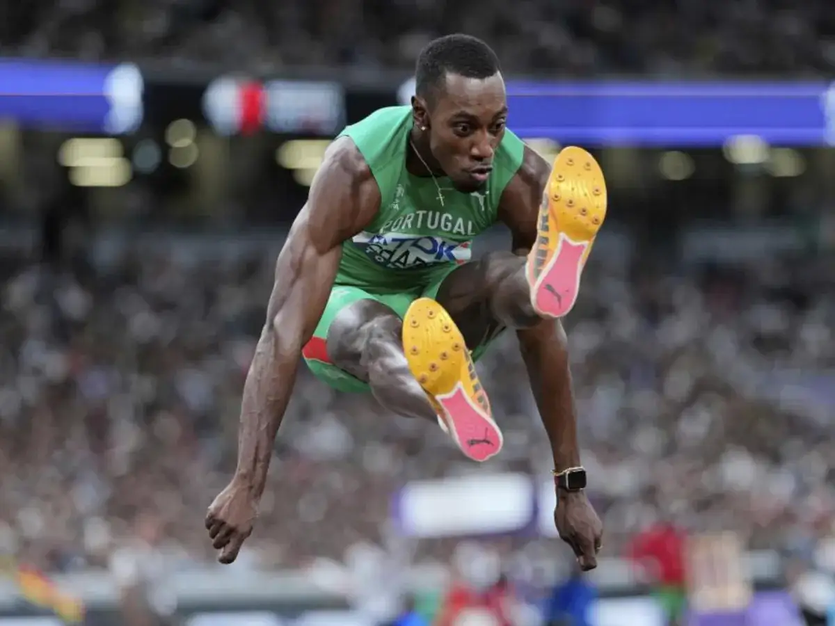 Pedro Pablo Pichardo en pleno salto triple, con su uniforme verde de Portugal, demostrando su potencia y concentración.