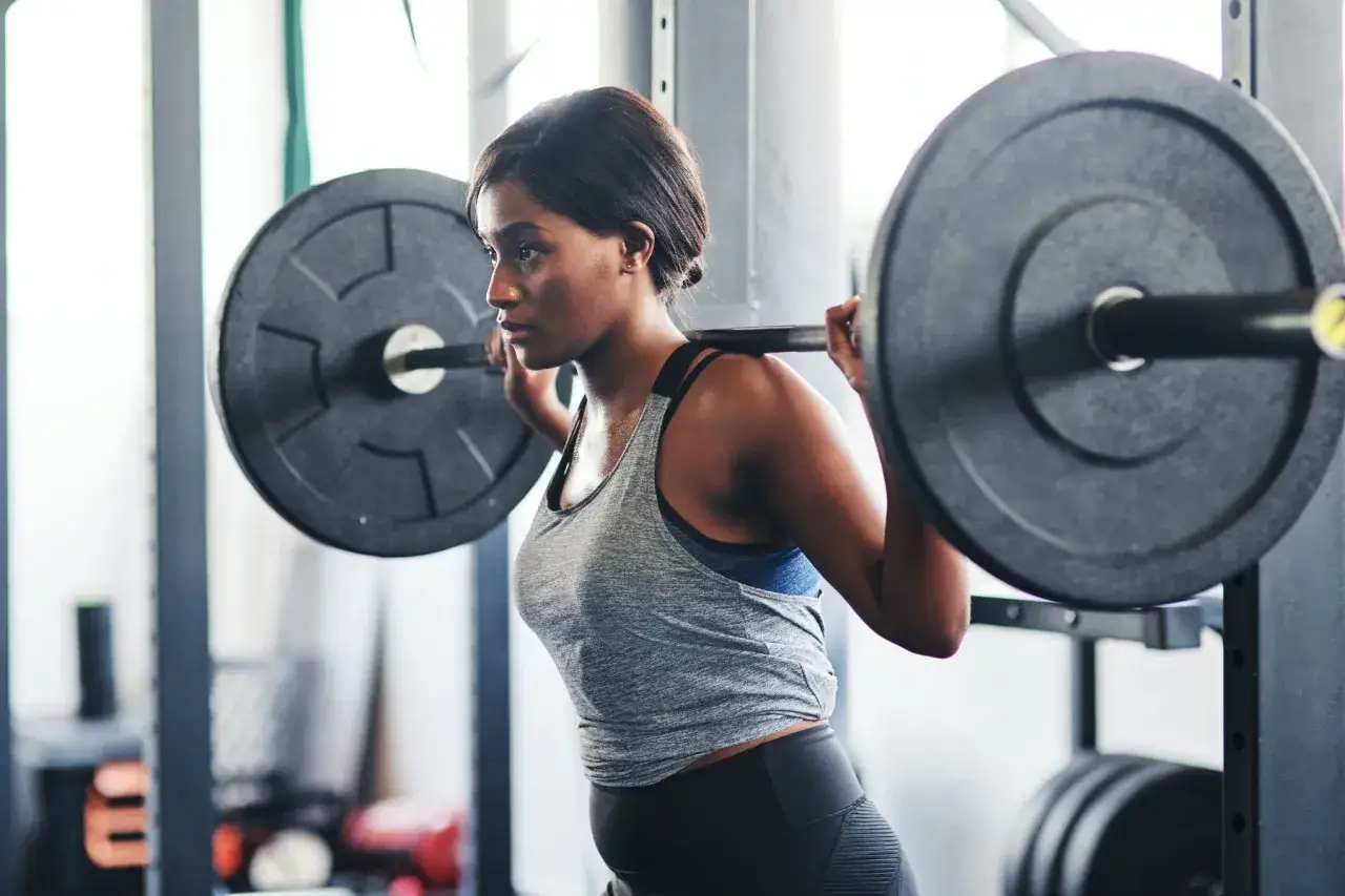 Mujer concentrada realizando ejercicios con barra en el gimnasio.