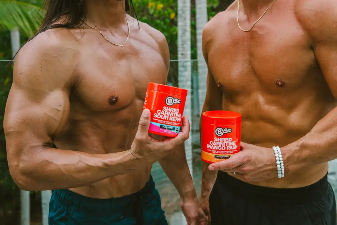 Dos hombres musculosos muestran envases de L-Carnitina, uno de