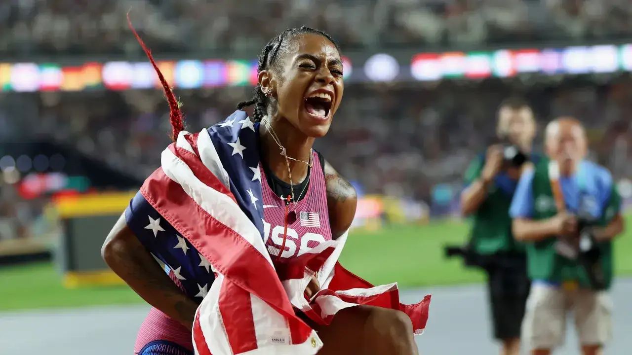 La campeona 100 metros femeninos atletismo, con la bandera de EE.UU., celebra su victoria con un grito de j&uacute;bilo.