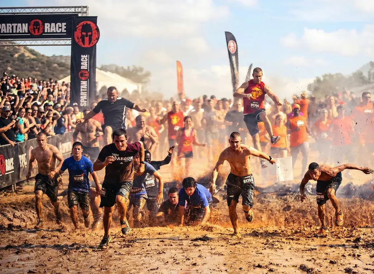 Corredores en una carrera de obstáculos, cubiertos de barro, en un verdadero entrenamiento espartano.