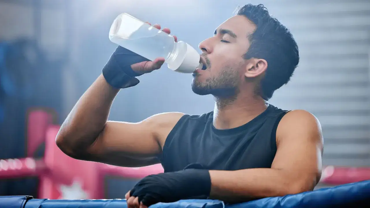 Boxeador se hidrata en el ring. Aprende como tomar electrolitos para recuperar energía tras el esfuerzo.