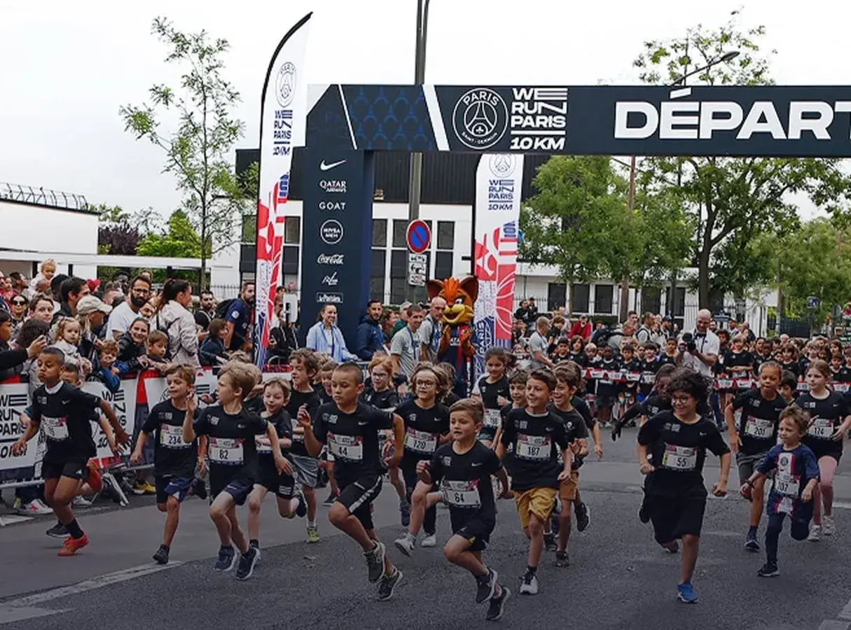 Ni&ntilde;os corren en el marat&oacute;n de Par&iacute;s, bajo un arco de salida con el logo 