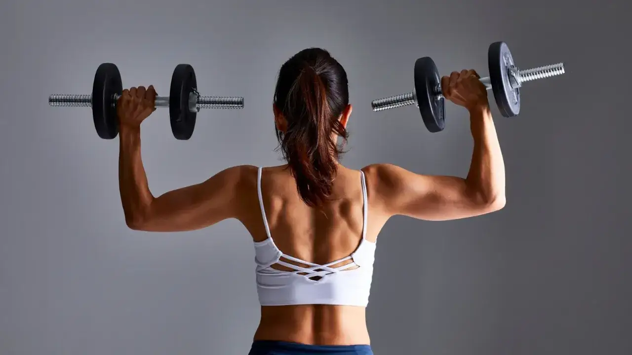 Mujer entrenando con pesas. Los BCAA para que sirven en mujeres es para la recuperación muscular y el crecimiento.