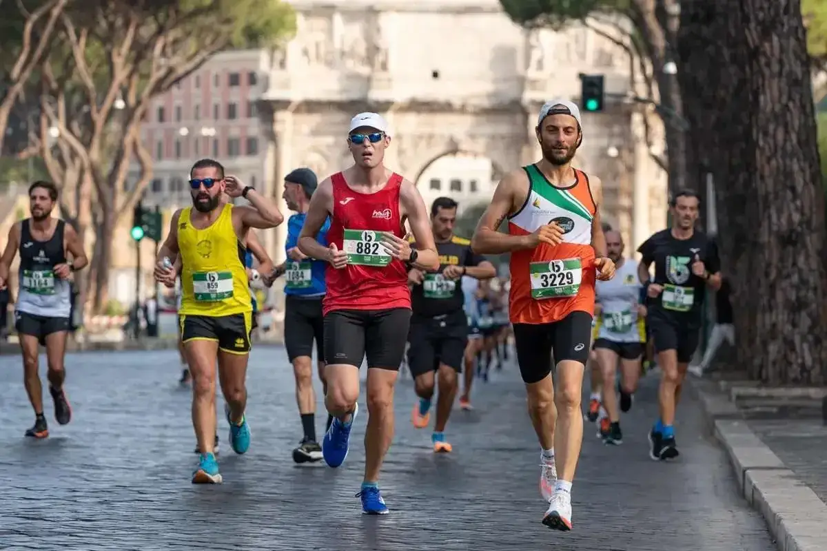 Corredores compiten en la media maratón Roma, con el Arco de Constantino de fondo.