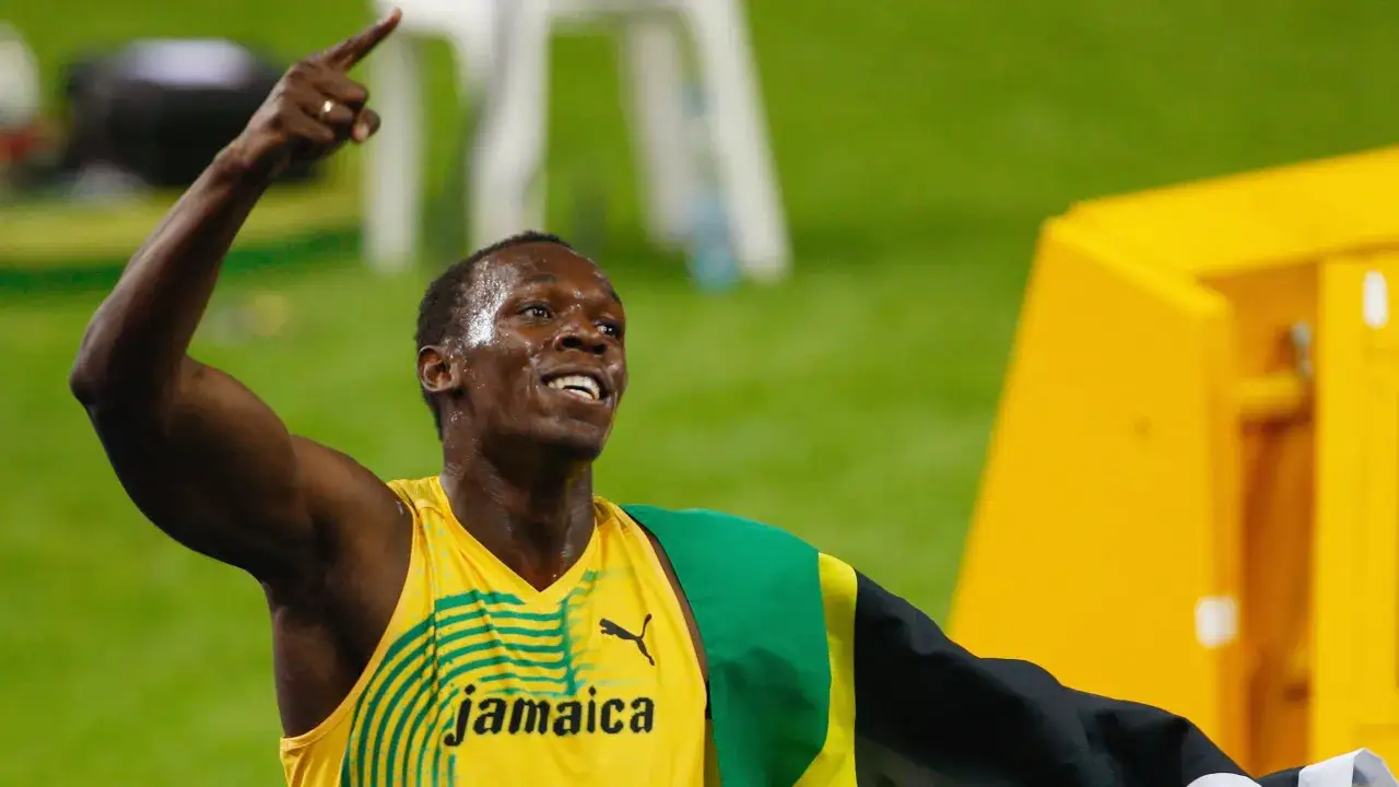 Usain Bolt celebra su récord en los 100m, con la bandera de Jamaica.