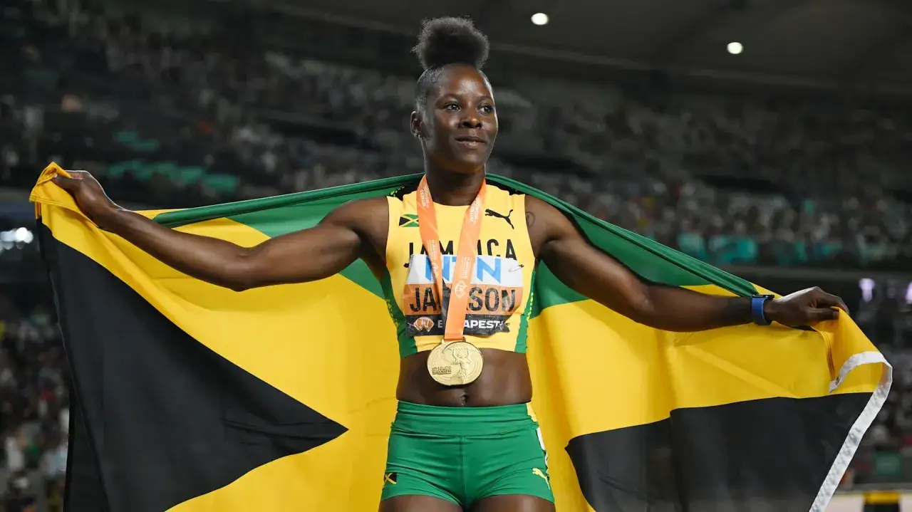 Shericka Jackson, atleta jamaiquina, celebra con la bandera de Jamaica y una medalla de oro.
