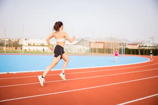 Mujer corriendo en pista de atletismo, lista para las noticias running.