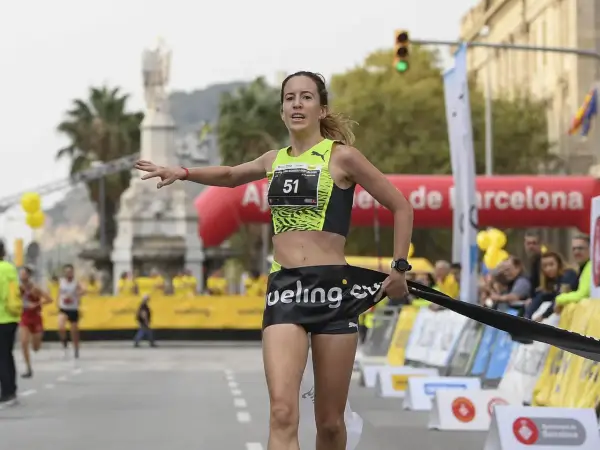 Meritxell Soler cruza la meta de una carrera en Barcelona, con el dorsal 51 y una expresión de esfuerzo.