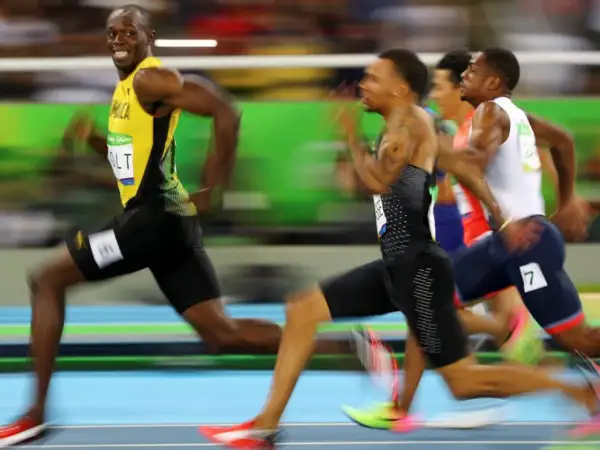 Usain Bolt, con su icónico uniforme amarillo, lidera la carrera de 100m, buscando batir su propio récord.