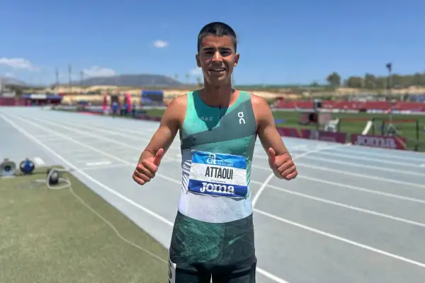Mohamed Attaoui, atleta sonriente con dorsal, da pulgares arriba en la pista de atletismo.