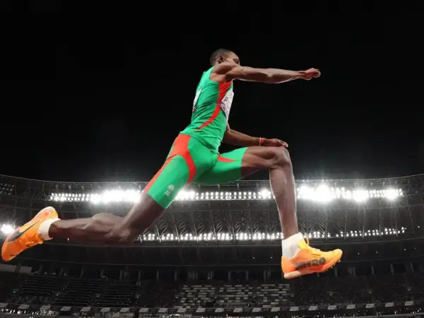 Pedro Pablo Pichardo en pleno salto triple, demostrando su potencia y técnica en el aire, con el estadio iluminado de fondo.