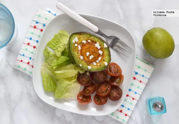 Aguacate horneado con queso y especias, acompañado de lechuga y tomates cherry. Un ejemplo de deliciosos alimentos cetogenicos.