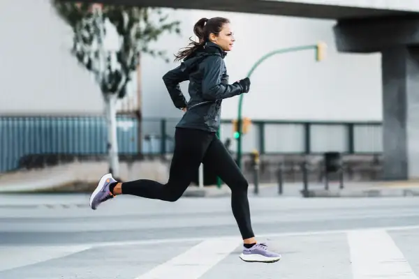 Mujer corriendo en la calle, demostrando una excelente técnica de carrera.