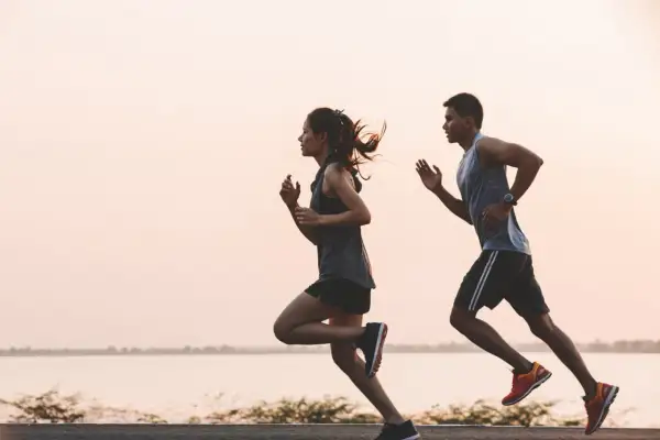 Pareja corriendo al amanecer. Para mantener la energía, es importante saber como tomar electrolitos.