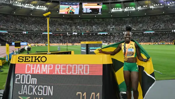 Shericka Jackson, campeona y récord en 200m, celebra con la bandera de Jamaica y su medalla de oro.