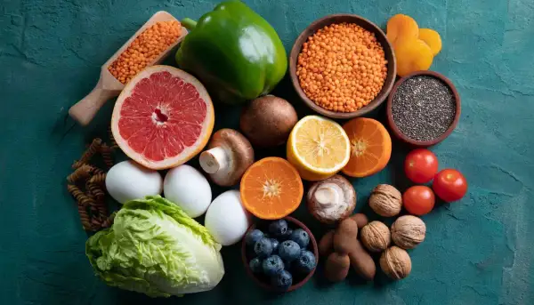 Variedad de alimentos alcalinos lista: lentejas, pomelo, pimiento verde, champiñones, limón, naranjas, tomates, arándanos, huevos, lechuga, pasta integral, semillas de chía, nueces y tamarindos.